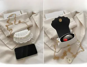 Detail view of white shell bag showing interior storage for phone and pearl gold chain