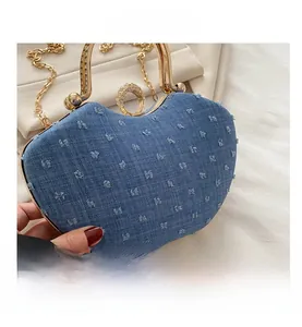 Detail of heart-shaped denim handbag with tassel texture and gold chain strap