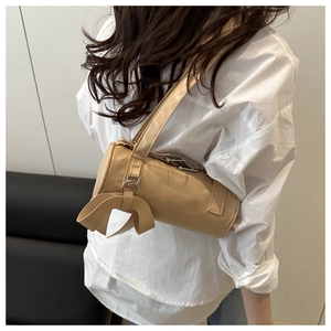 Close-up of stylish beige cylindrical shoulder bag with elegant bow detail on the side