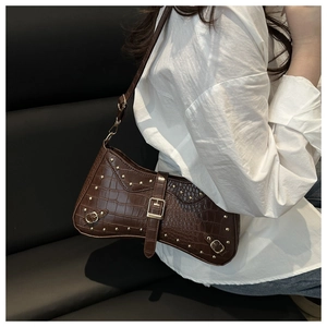 Close-up of dark brown crocodile pattern shoulder bag with gold rivets and buckle