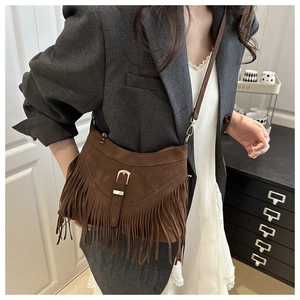 Detail of brown suede tassel crossbody bag featuring fringe trim and golden buckle