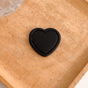 Detailed close-up view of a minimalist matte black heart-shaped phone ring holder on wood