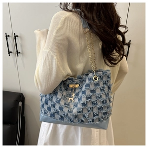 Close-up of denim tote bag featuring checkerboard weave, frayed edges and deer charm