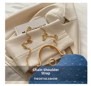 Detail of blue denim box bag featuring gold metal handle and crystal-encrusted rings