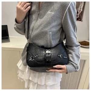 Close-up of black crocodile pattern shoulder bag with silver buckles and rivets detail