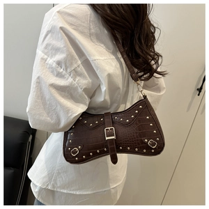 Detail of vintage brown crocodile embossed baguette bag with golden studs and metal buckle