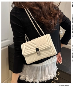 Détail du motif matelassé en V sur le sac bandoulière blanc cassé avec chaîne argentée