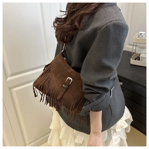 Detail of dark brown suede fringe shoulder bag with silver buckle and bohemian tassels