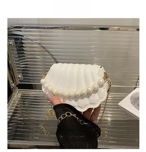 Detail of shell-shaped white leather bag with vertical quilting and pearl chain ornament