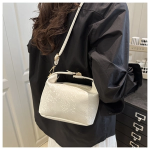 Detailed close-up of white snake-embossed pattern and gold hardware on retro handbag