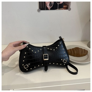 Detail of black crocodile embossed shoulder bag featuring gold studs and buckle accent