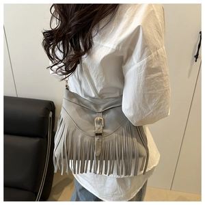 Detail of grey suede shoulder bag with long fringes and metal buckle bohemian style