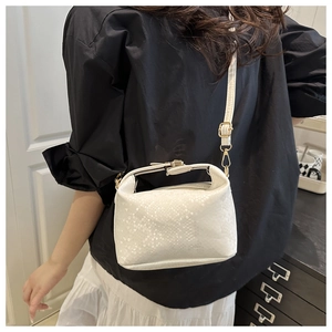 White embossed pillow bag with gold hardware shown on a model in a minimalist setting