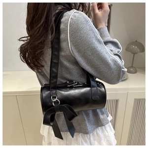 Detail of black cylindrical shoulder bag with large bow and silver hardware