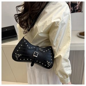 Detail of black faux crocodile leather shoulder bag with gold rivets and buckle closure