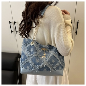 Detail of denim patchwork tote featuring star patterns and gold chain leather straps