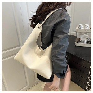 Gros plan d'un grand sac cabas minimaliste en cuir grainé crème avec des œillets en métal