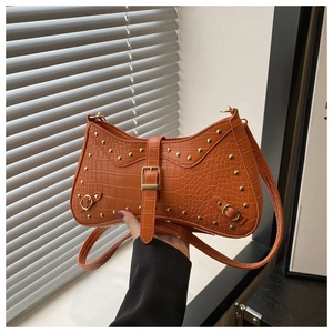 Detail of orange crocodile pattern bag with gold studs and adjustable buckle strap
