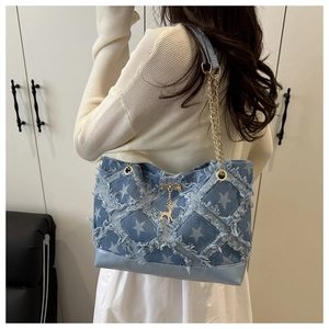 Detail of denim tote bag showing frayed edge star pattern and gold deer charm pendant