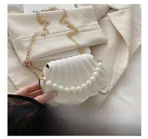 Detail showing white shell-shaped mini bag with pearl handle and golden chain strap