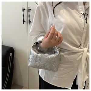 Detail of silver snake-pattern mini handbag with metallic finish and gold hardware handle
