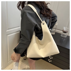 Close-up of cream white hobo tote bag with wide shoulder strap and silver metal ring detail