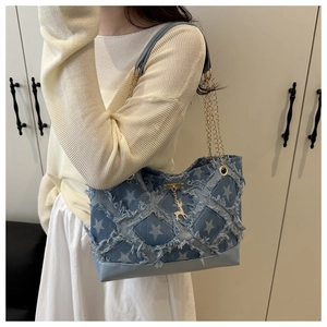 Detailed shot of denim tote featuring star patterns, frayed edges, and a golden deer charm