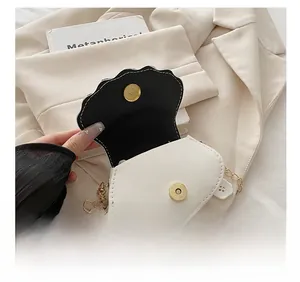 Detail view of white shell bag showing inner lining and golden magnetic metal clasp