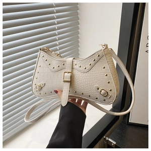 Detail of white crocodile pattern shoulder bag with gold rivets and leather buckle strap