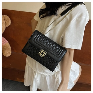 Detail of black quilted leather crossbody bag with vintage chain and gold diamond clasp