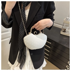 Detail of white sequined evening clutch with gold metal handle and chain strap