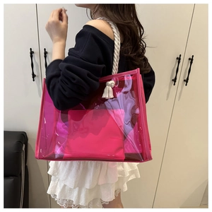 Detail of pink transparent PVC tote bag featuring white rope handles and decorative tassels