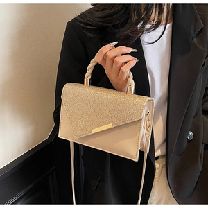 Détail d'un sac à main beige élégant avec rabat doré pailleté et poignée torsadée chic