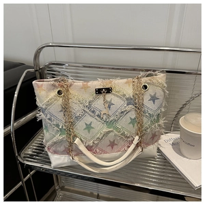 Close-up of star pattern tote bag with frayed edges and luxury gold chain handles