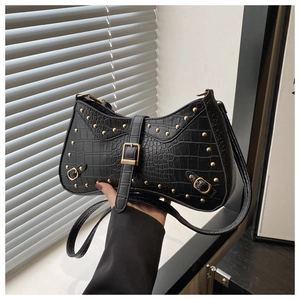 Detail of black crocodile texture shoulder bag with gold rivets and vintage metallic buckles