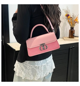 Close-up of pink crossbody bag with silver buckle worn by model against soft background