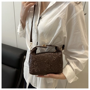 Macro view of dark brown snakeskin embossed leather bag with gold metal buckle and strap