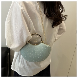 Detail view of mint green shell bag with gold handle and sparkling diamond lock