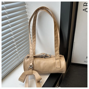 Dettaglio di una borsa a cilindro beige con trama in morbida pelle e decorazione con fiocco