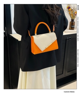 Détail du sac à bandoulière en cuir orange avec rabat tissé beige et bordure en métal