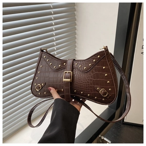 Detail of brown crocodile pattern shoulder bag with gold rivets and wave shape design