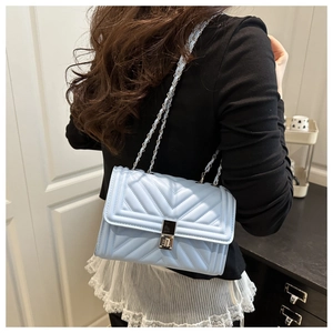Sac bandoulière matelassé bleu clair avec chaîne argentée porté par un mannequin