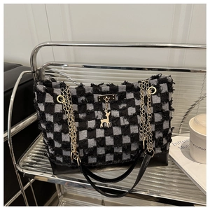 Detail of tweed checkered tote bag with gold chain strap and decorative deer charm