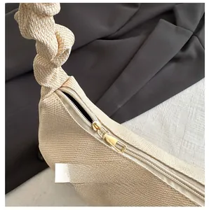 Detail of smooth gold metal zipper and woven texture on beige underarm bag
