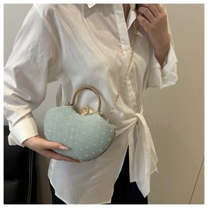 Close-up of mint green rhinestone evening bag with gold handle and chain strap on a model