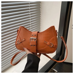 Macro detail of orange crocodile pattern shoulder bag with silver buckle and rivets