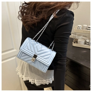 Sac bandoulière matelassé bleu clair avec chaîne argentée porté par un mannequin