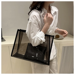 Detailed view of large transparent PVC tote bag with black trim and rope handles on a model