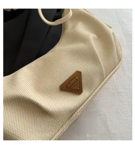Detailed macro shot of a cream woven shoulder bag featuring a vintage triangular metal logo