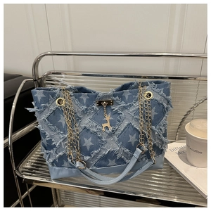 Detail view of denim tote bag with star prints, frayed edges and golden deer charm